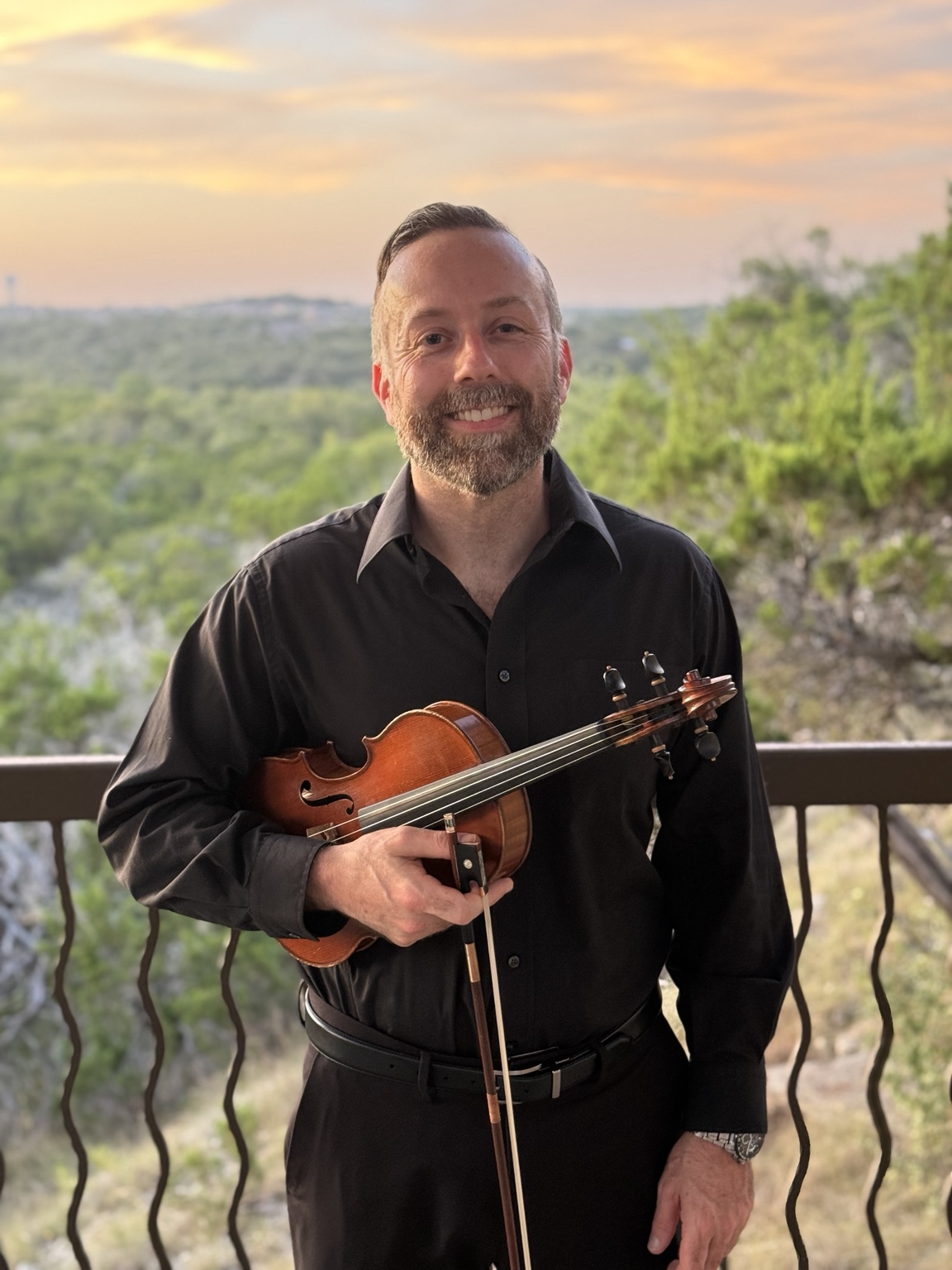 David Price holding his violin at sunset