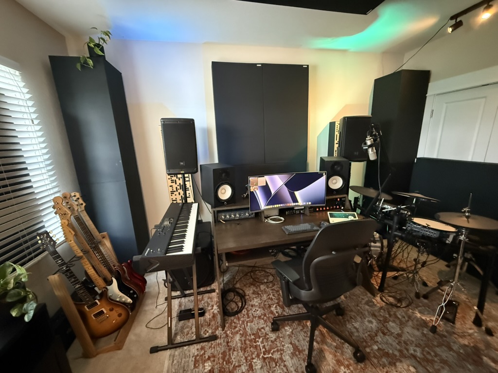 Wide view of David Price’s recording and production studio with instruments, monitors, keyboards, and drums