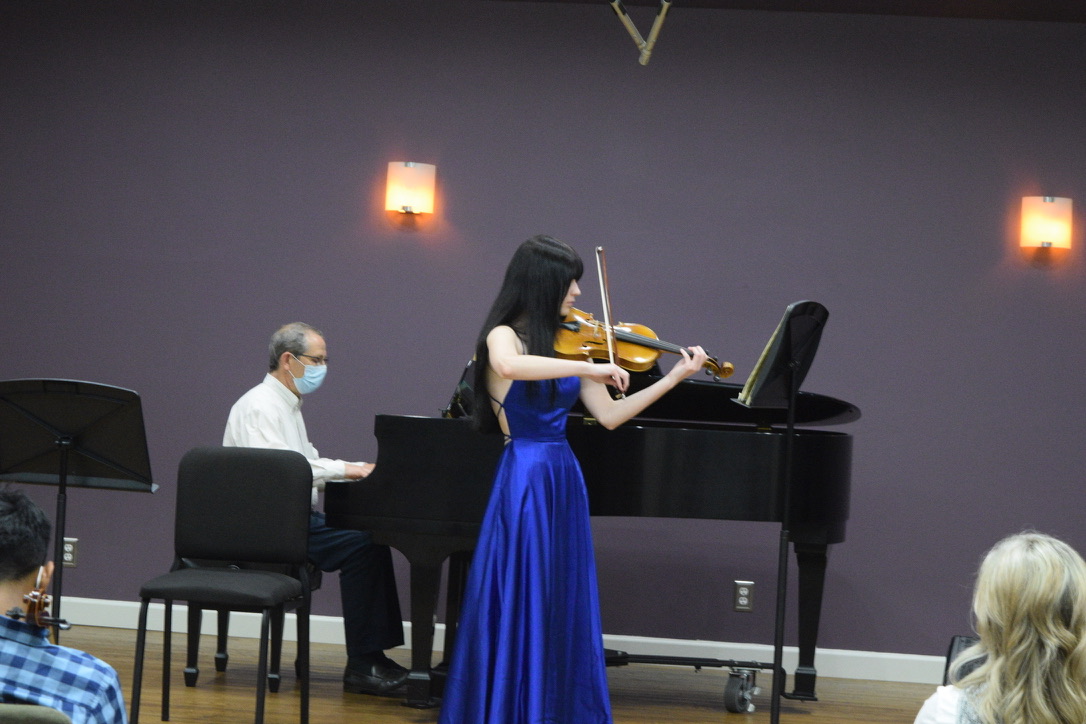 Violin student performing in a blue concert dress with piano accompaniment