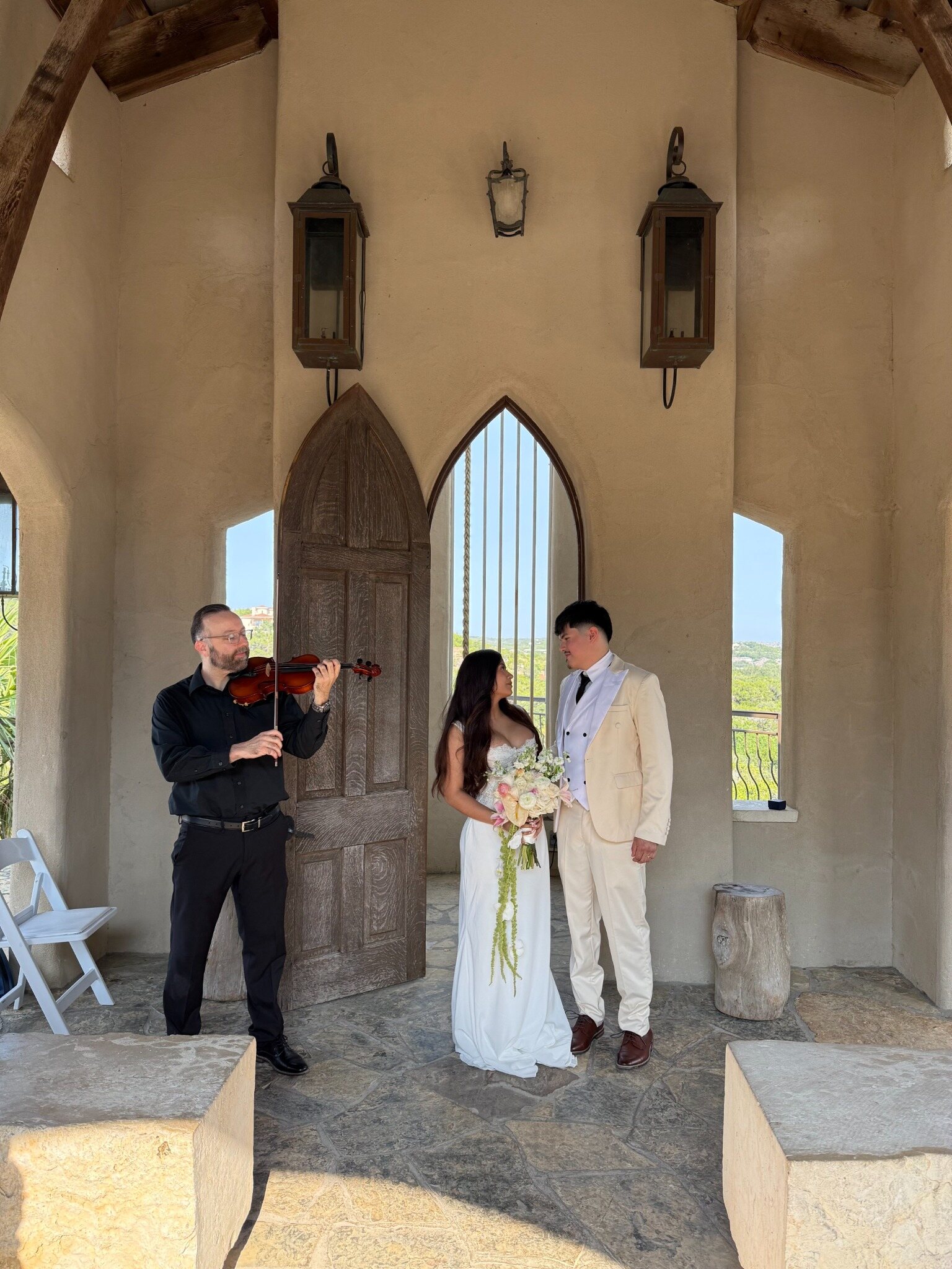 David Price performing violin beside a bride and groom at an outdoor wedding